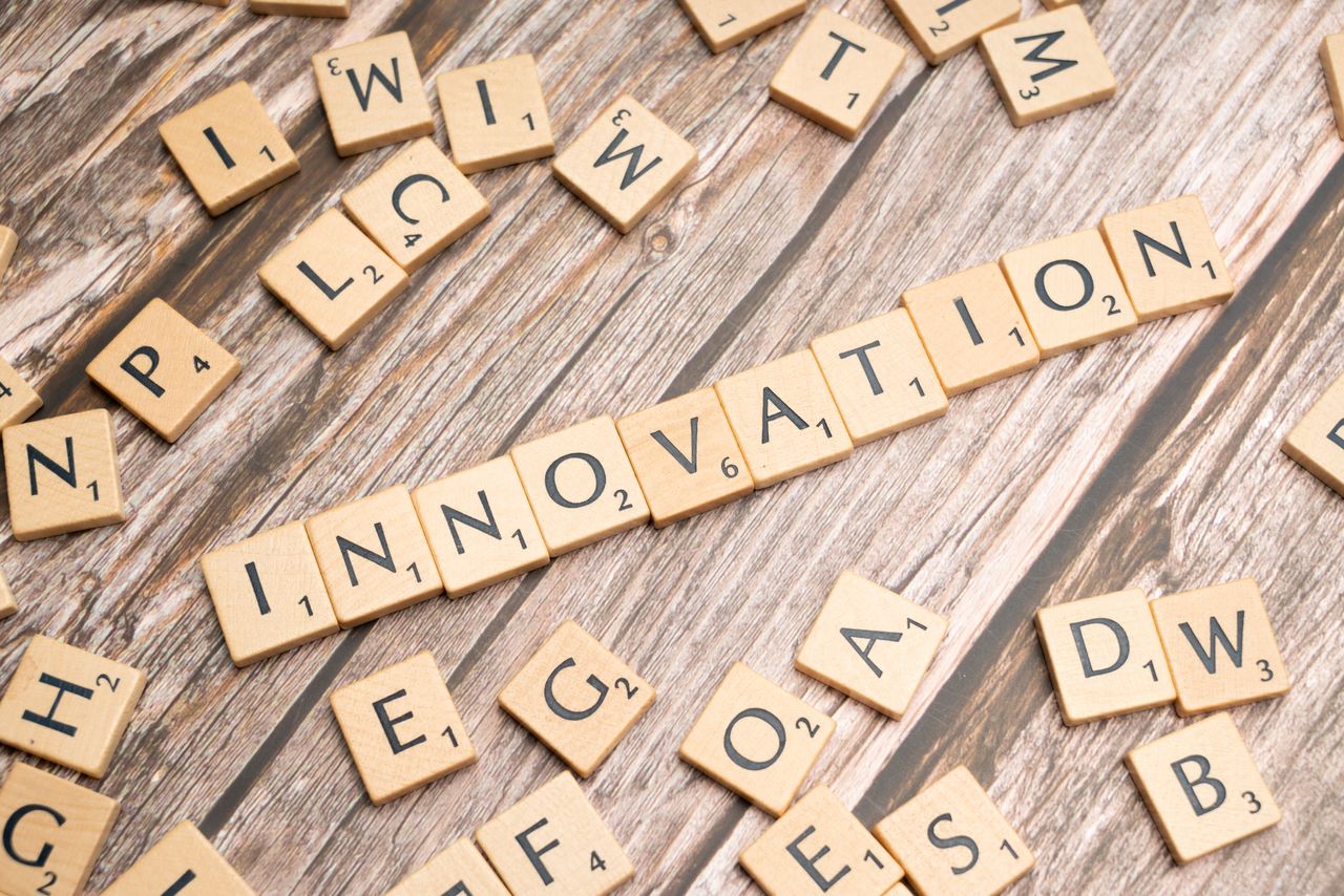 about-us-02 Creative display of 'Innovation' spelled with wooden letter tiles on a wooden surface.